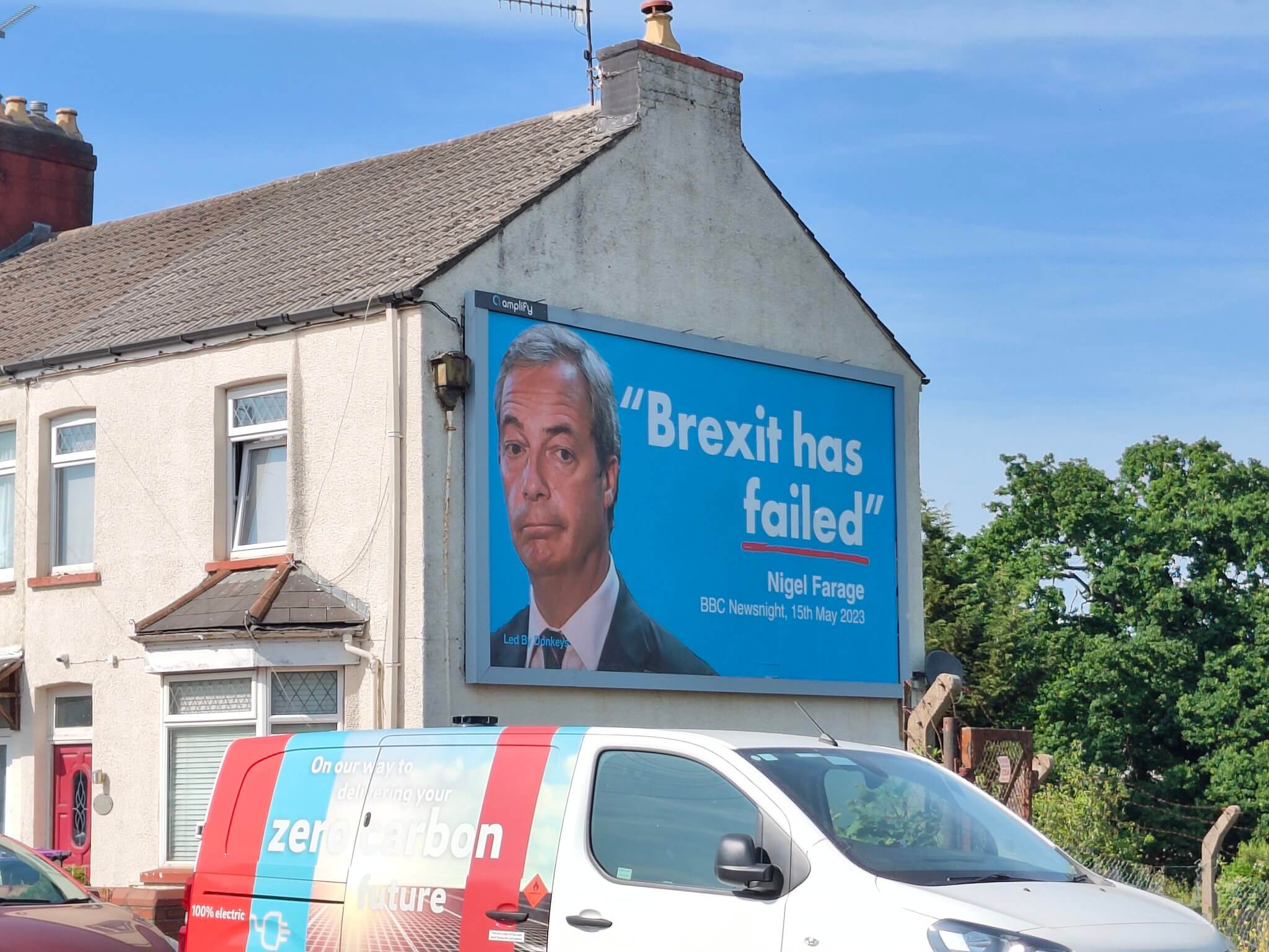 large poster of nigel farage on side of house