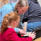 a woman used an ipad helped by a young girl