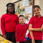 two boys and a girl sell refreshments in a school