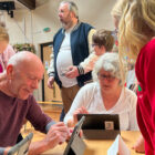 two older pupil use ipads watched by pupils