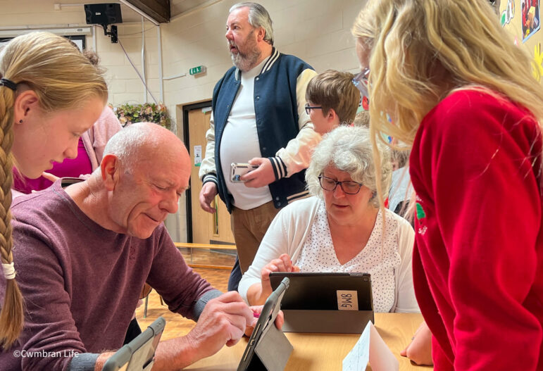two older pupil use ipads watched by pupils