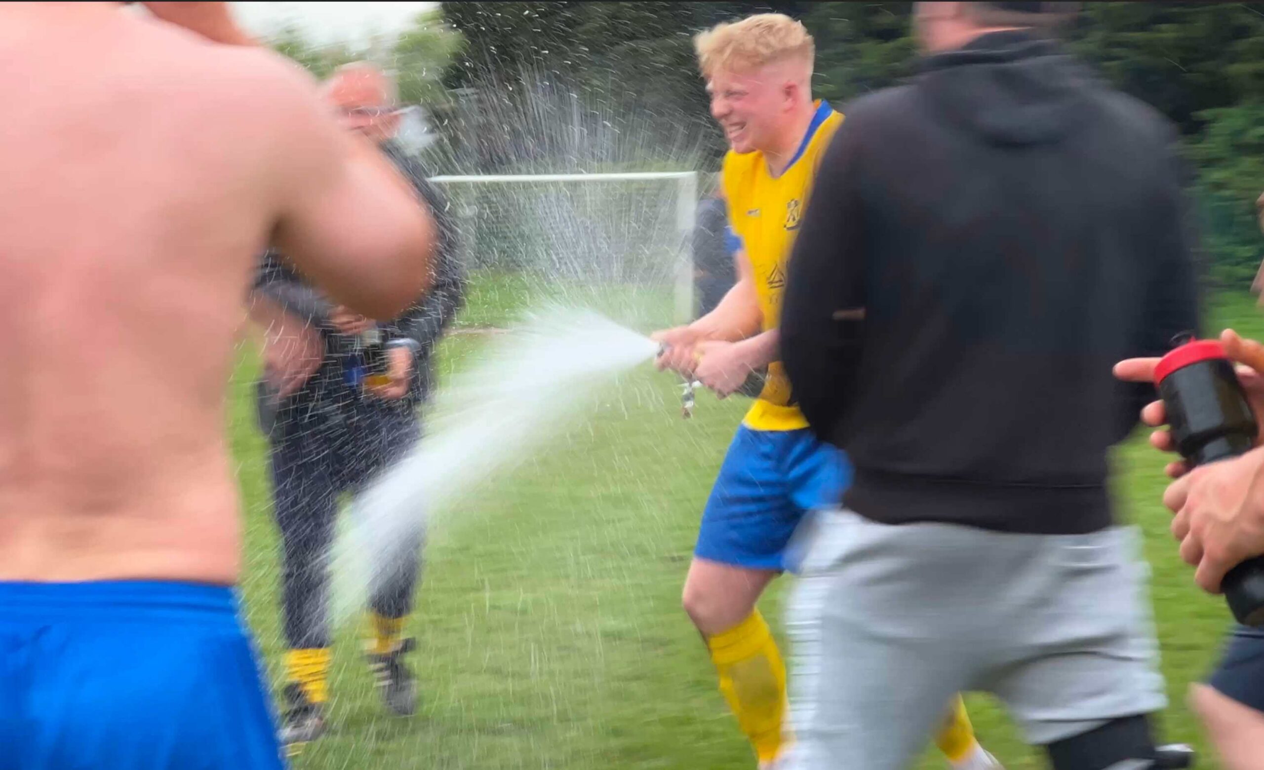 a football player sprays a bottle of champagne to celebrate a win