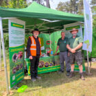 three men stood under a green gazebo