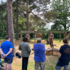 a group of people watch three men dressed in military uniform at a re-enactment event