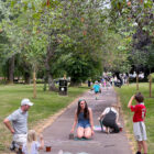 a long path covered in chalk art with some adults and children drawing on it