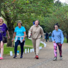 four women walk wearing headphones