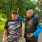 two men, one holding a wooden baton