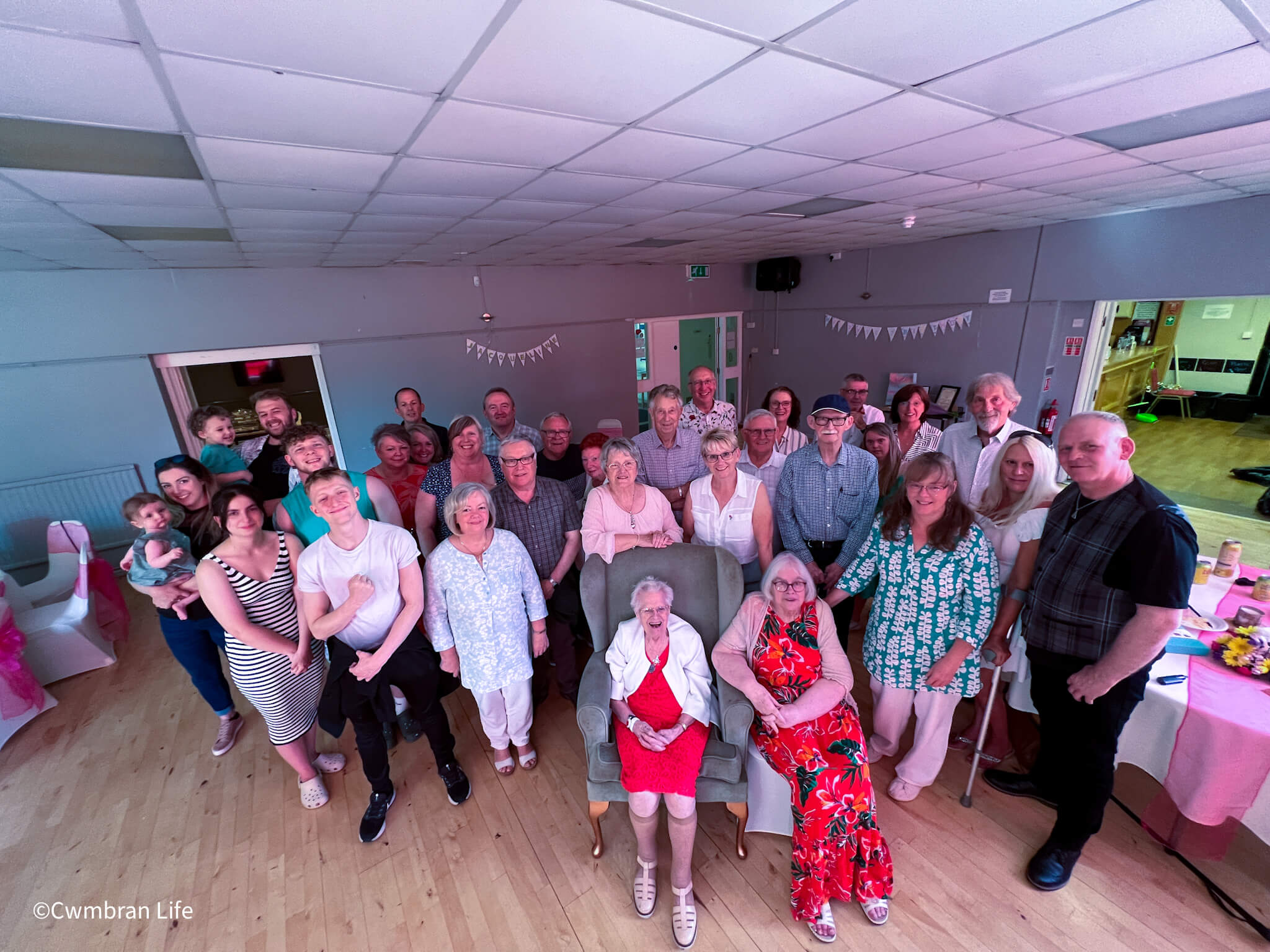 a large group of people stood around their relative who is 100