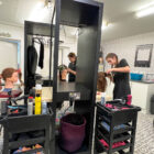 three hairdressing students cut hair on plastic models