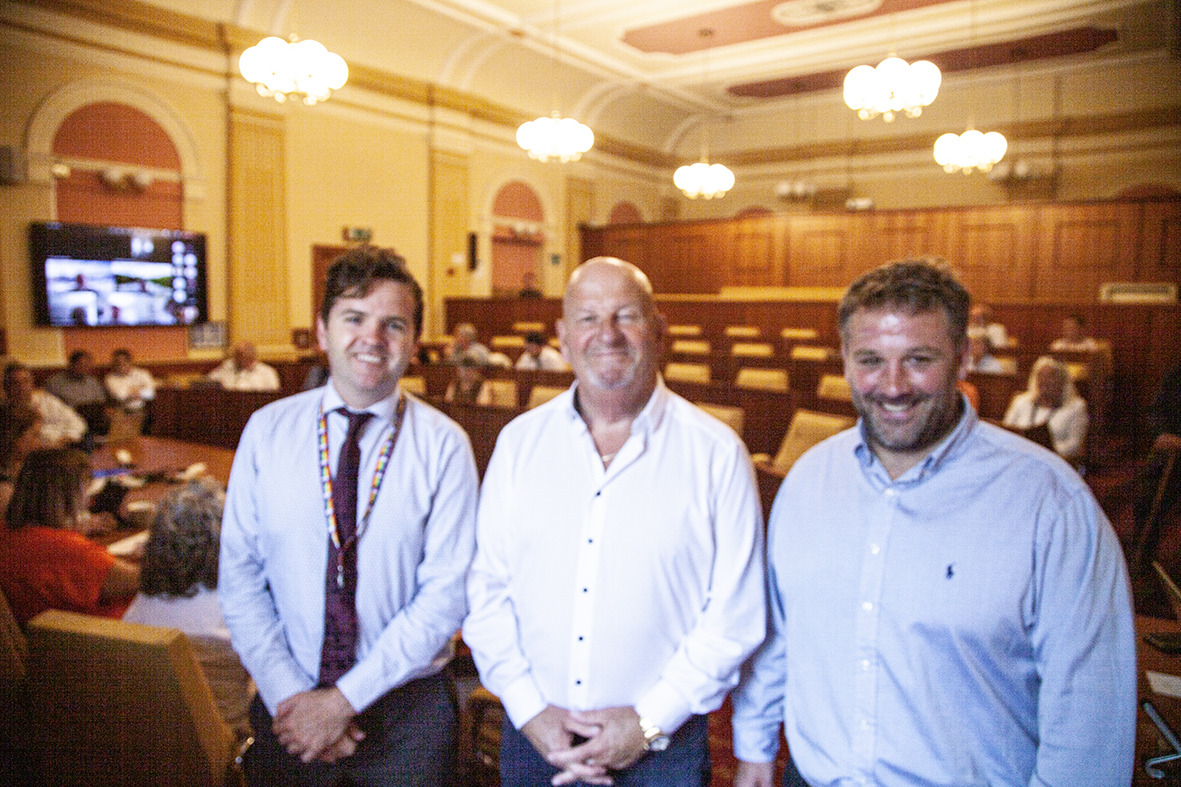 three men in a council chamger