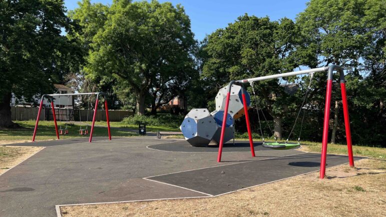 a play park including swings and large blocks to climb on