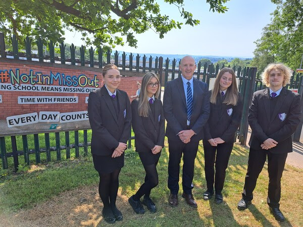 four pupils and a headteacher outside a school