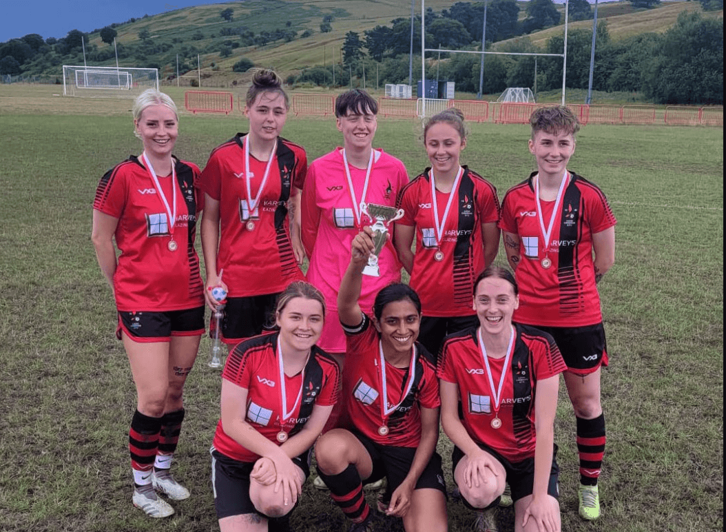 a women's football team wear medals after winning a tournament