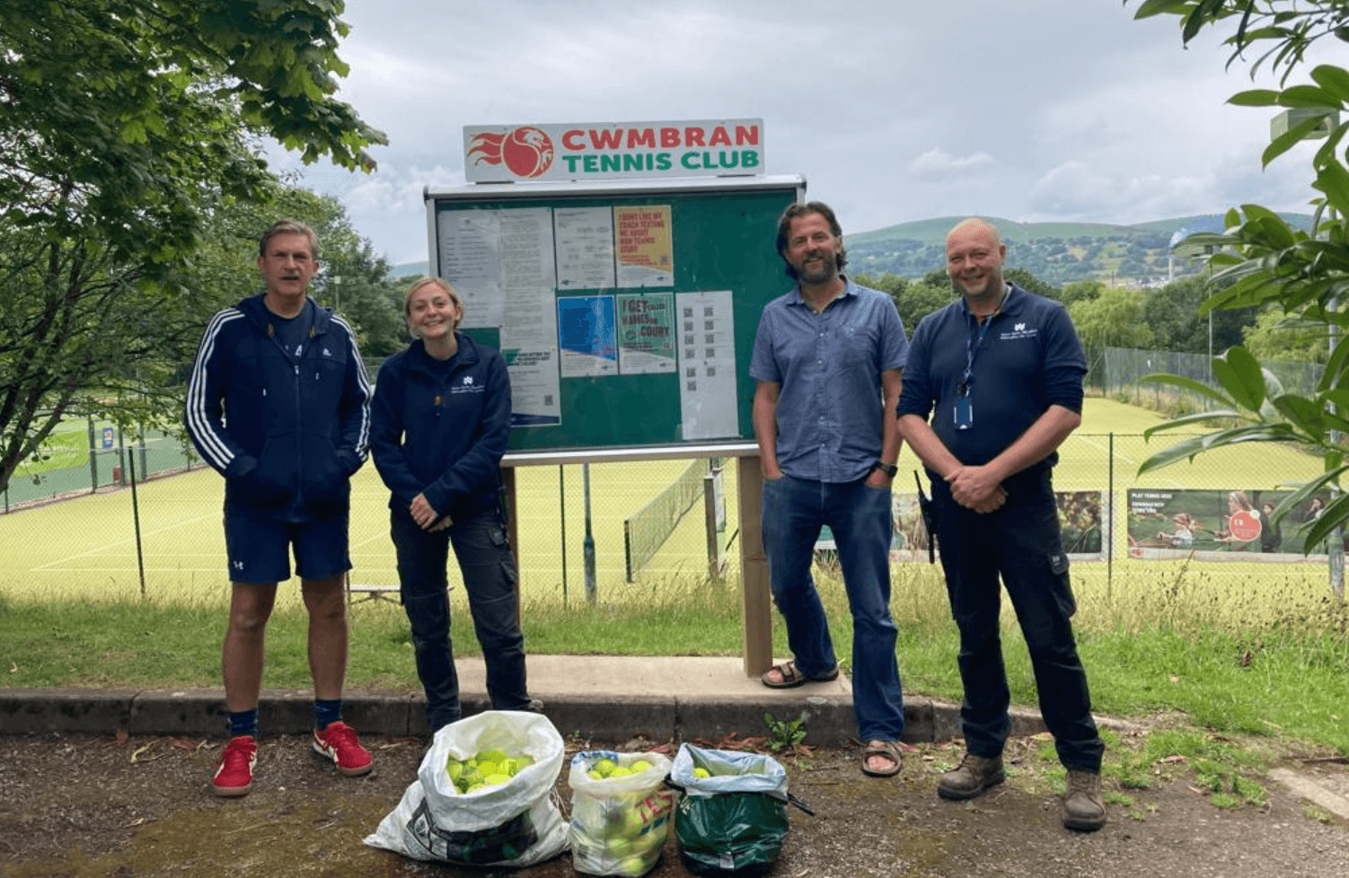 four people stood by a tennis court