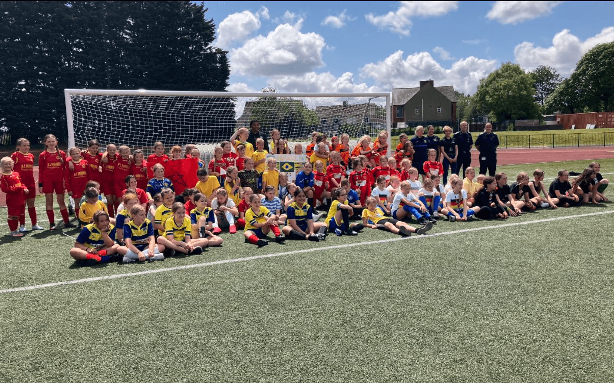 a large group photo of girls on a football pitch