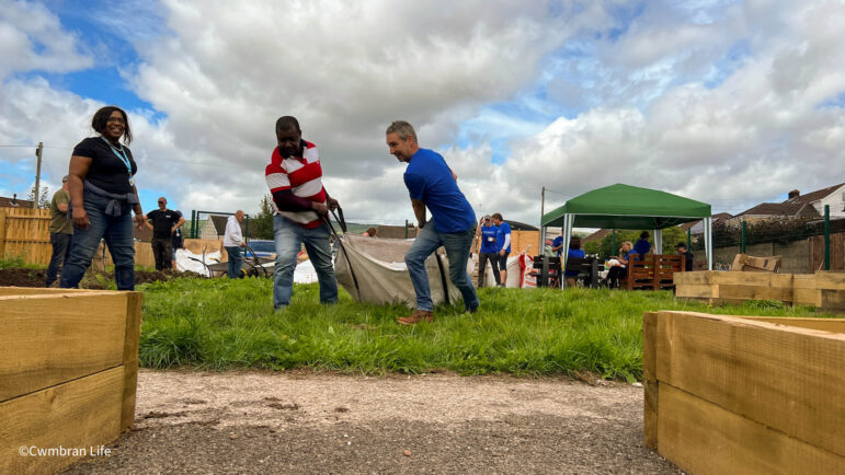 two men drag a large bag of soil