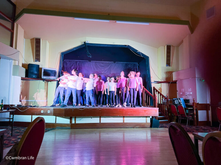 group of young people on stage sing and dance