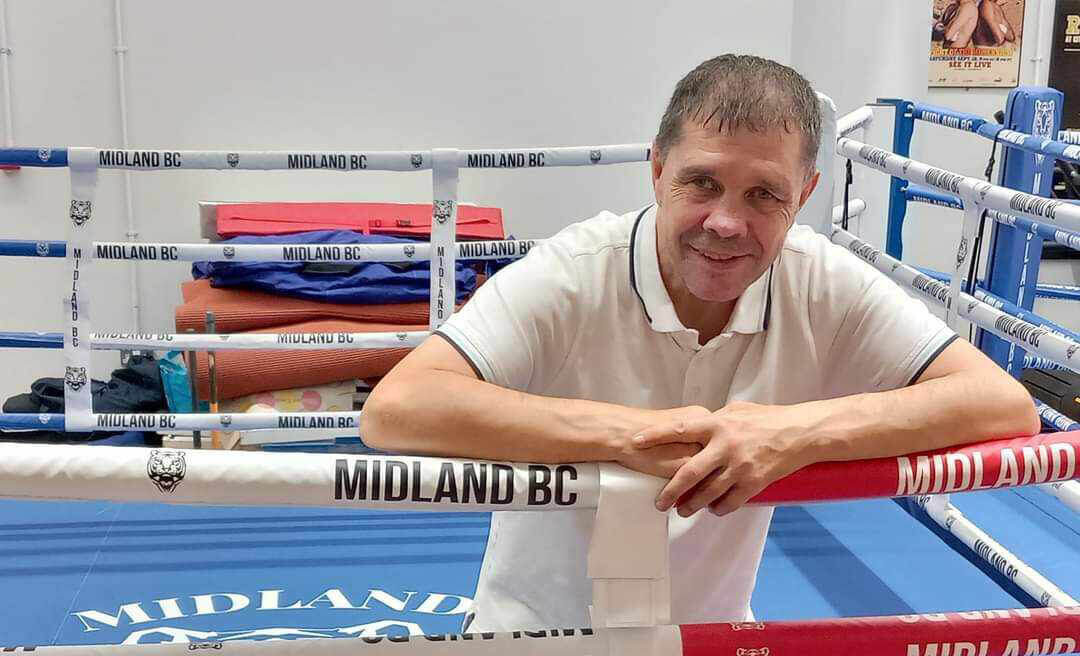 man in a boxing ring leaning over ropes