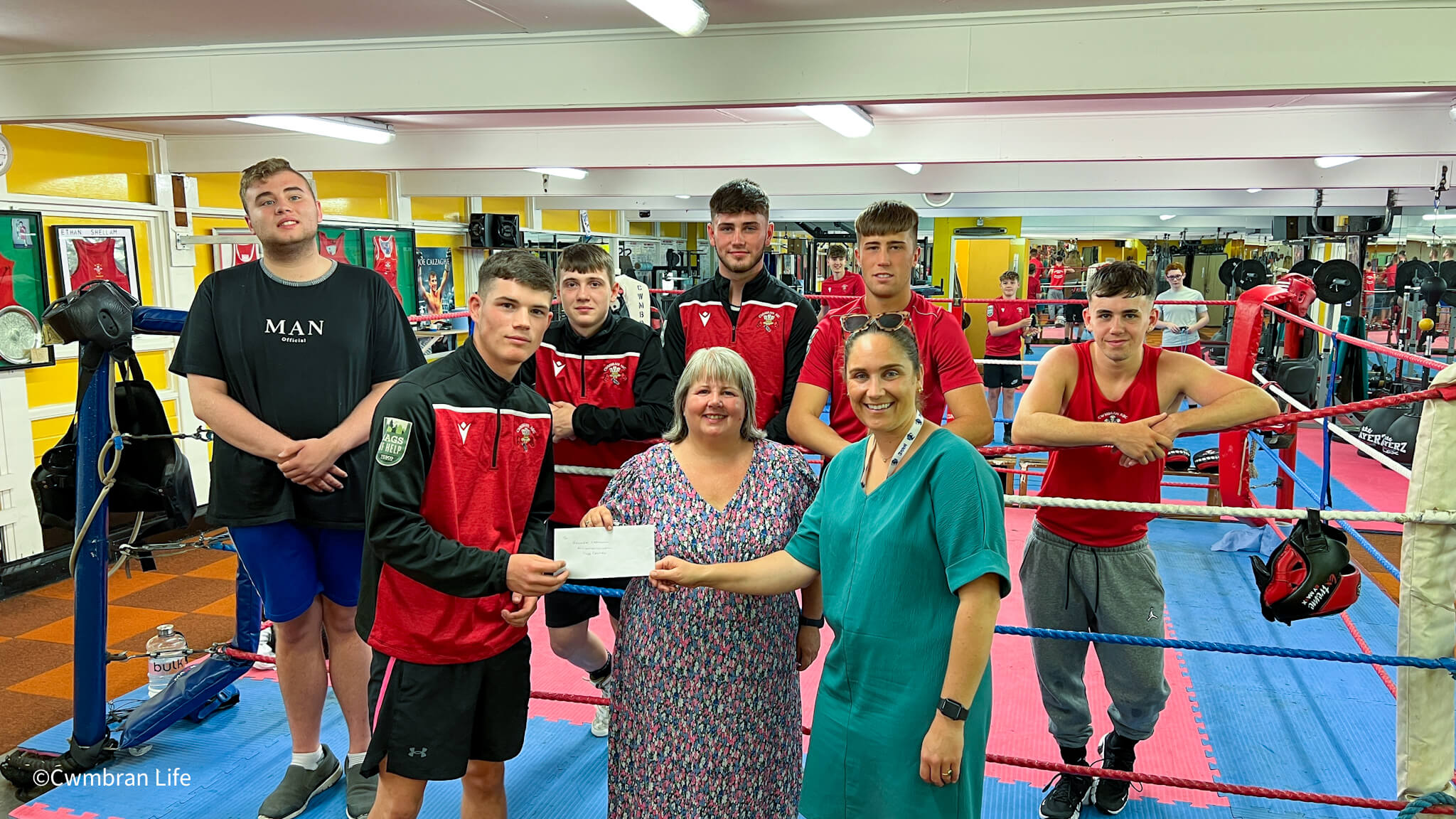 a group of boxers present a cheque to two women
