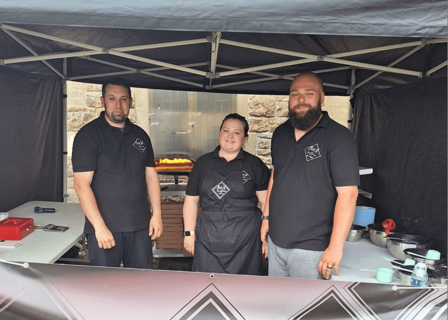 two men and a woman on a pizza stall