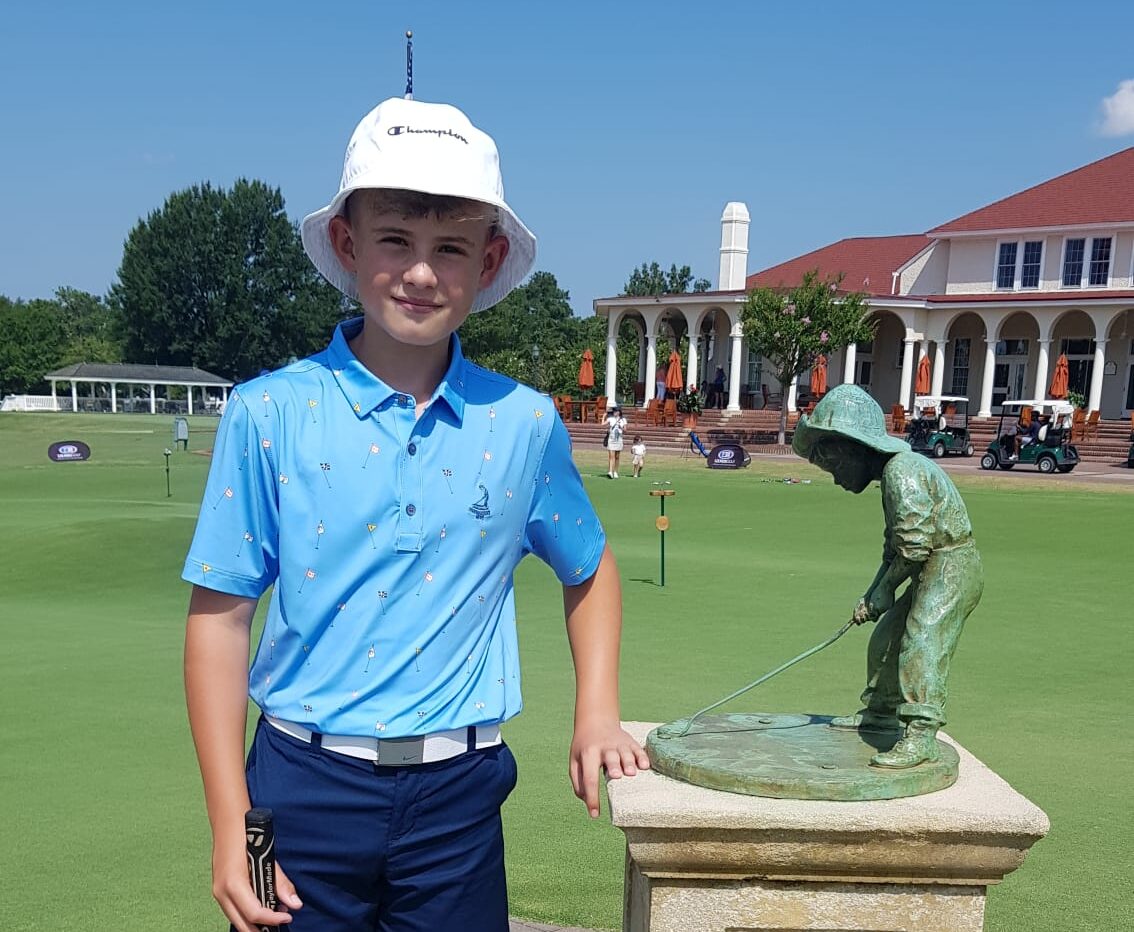 a boy stood next to a golf statue