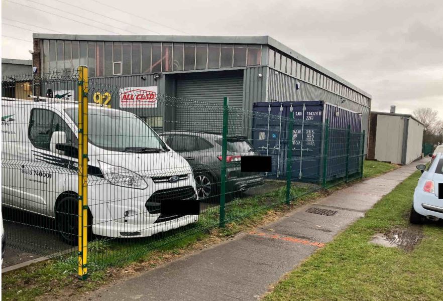 vans and cars parked behind a fence