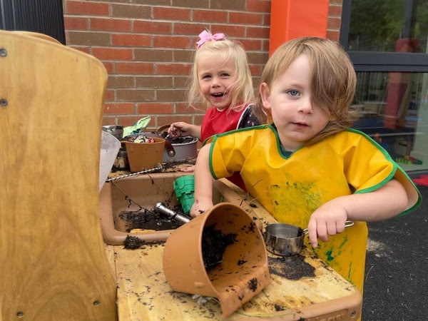 two children enjoy playing with gardening toys