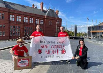 four protestors hold a banner calling for rent control in Wales
