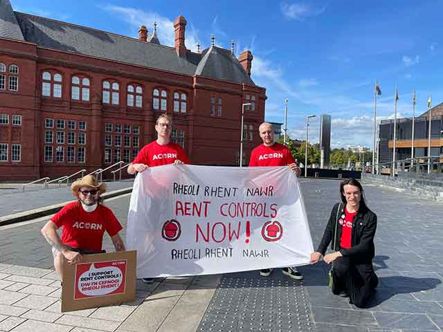 four protestors hold a banner calling for rent control in Wales