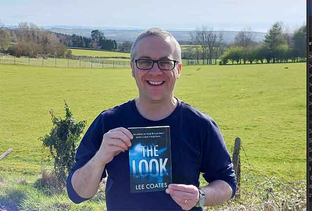lee coates holding a copy of his book