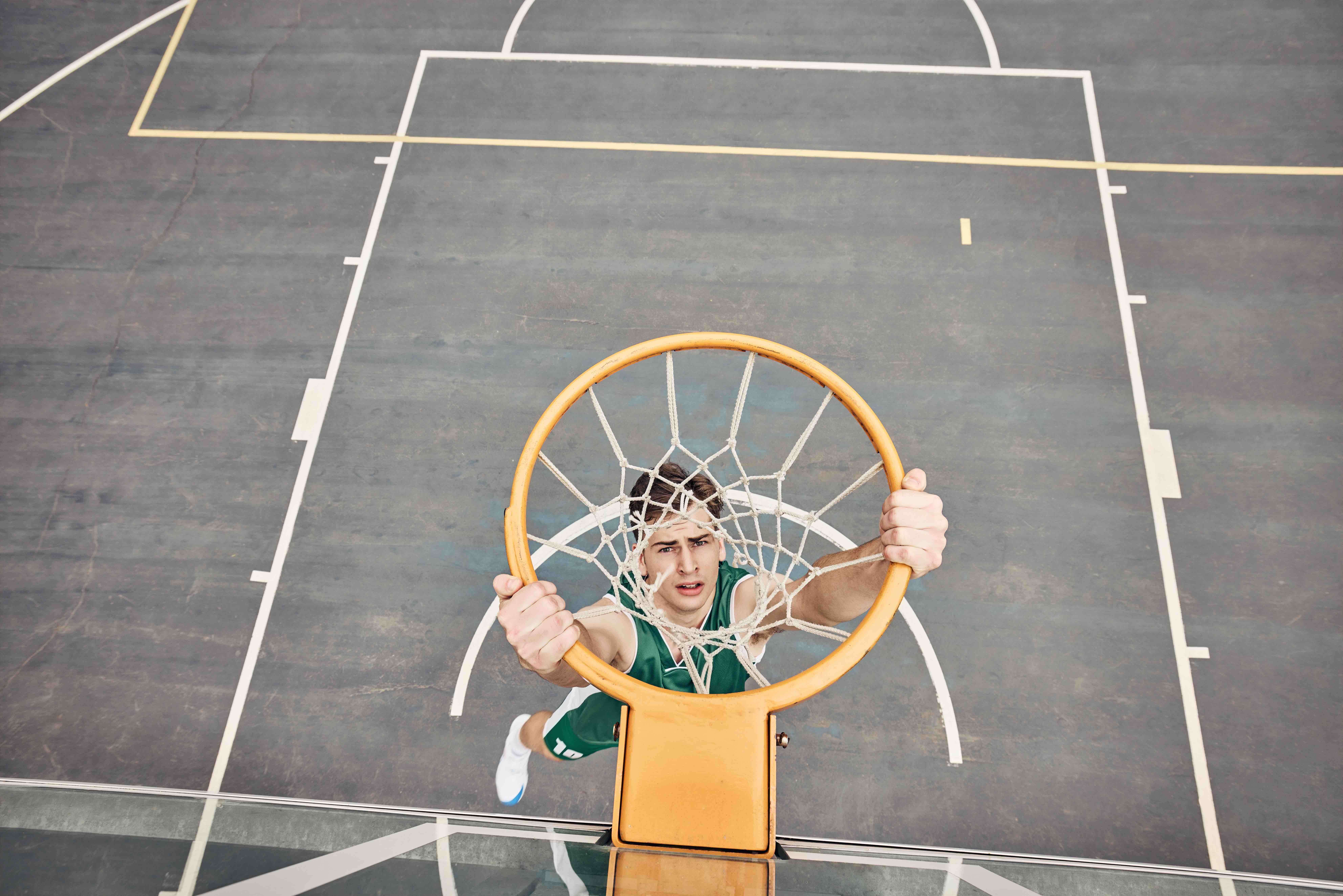 man hanging from basketball net