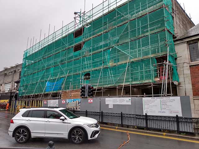 a building covered in scaffolding and green sheeting