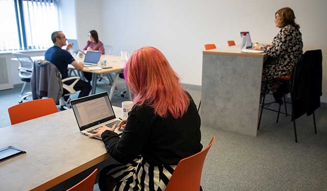 four people working on laptops in a room