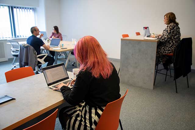 four people working on laptops in a room