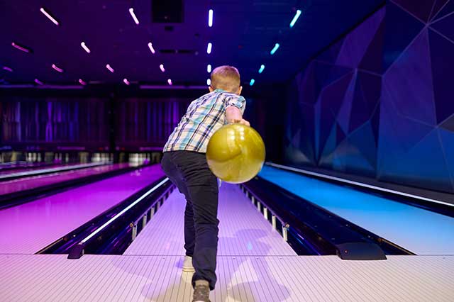a boy bowls a bowling ball