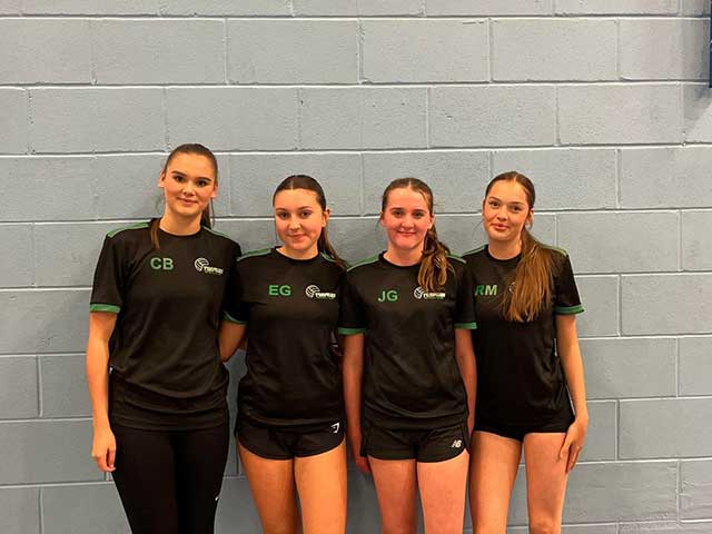 four netball players stood by a wall