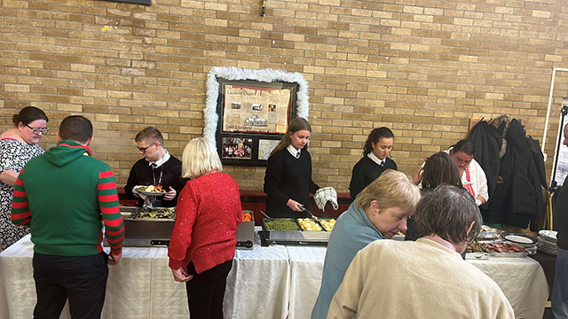 pupils serving dinner in a community hall