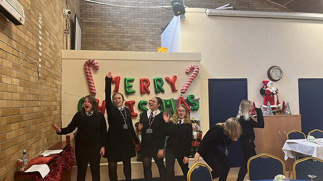 five pupils sing in a community hall