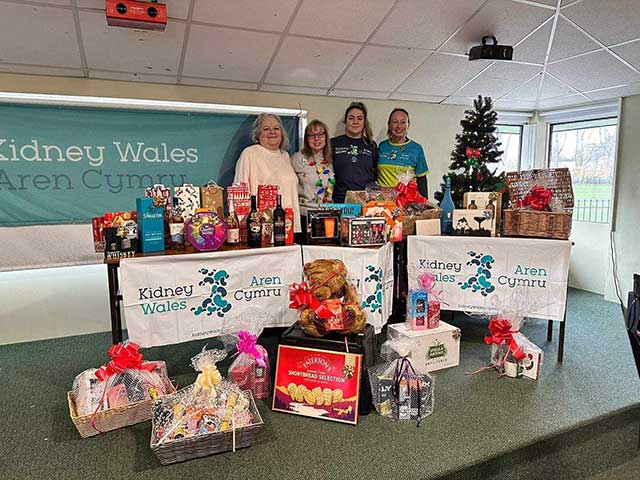 four women stood by a table of raffle prizes