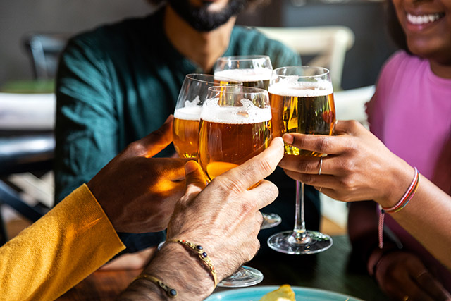 group of friends tap glasses in a pub