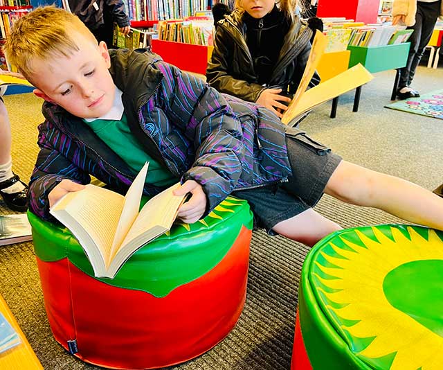 a boy reading a book in a library