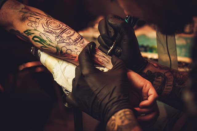 a tattooist creates a tattoo on an arm