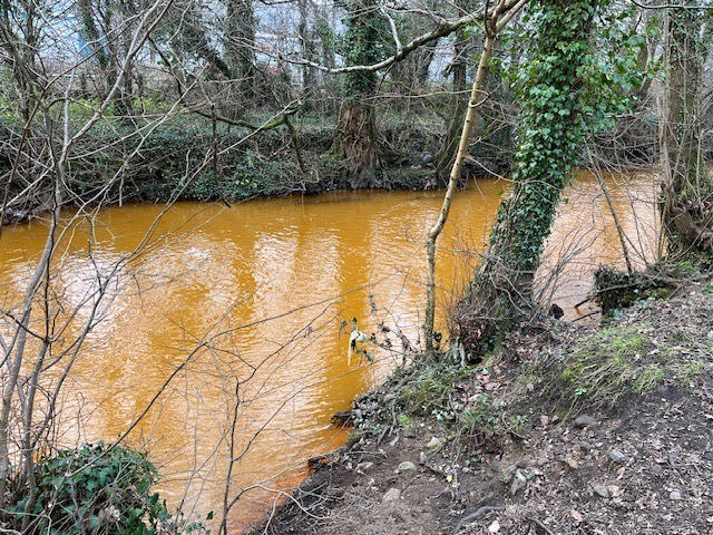 the afon lwyd river is orange following a pollution incident