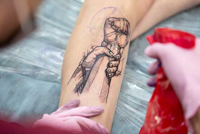 a tattooist sprays an arm