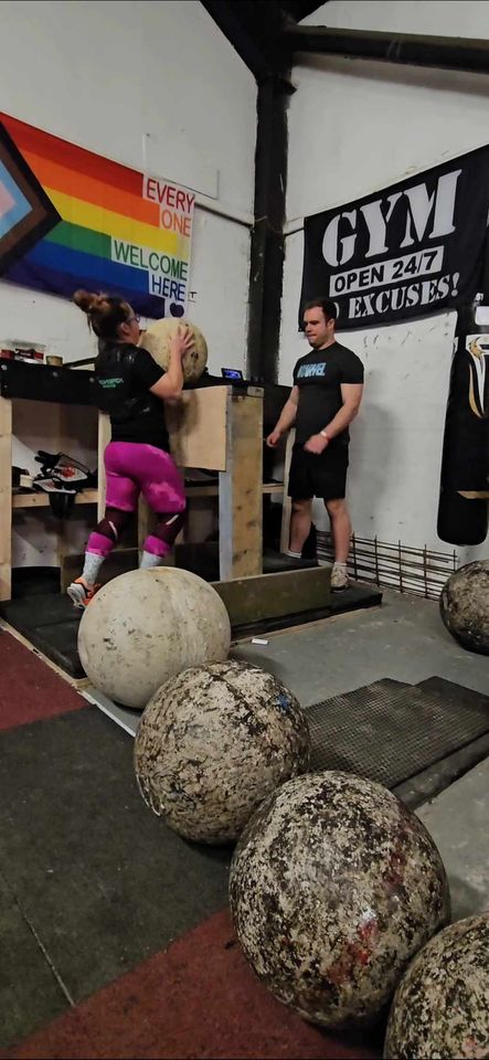 woman lifts rounds ball onto stand in a gym