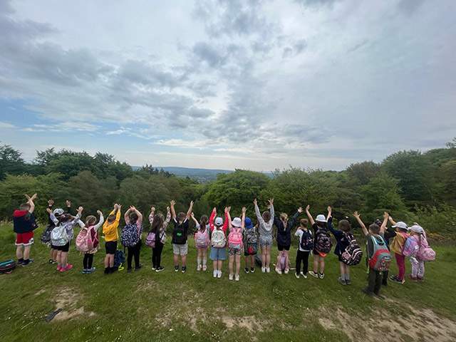 pupils on a hill hold hands in air