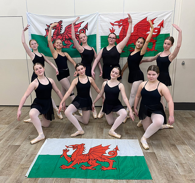 ten dancers stand by a wales flag
