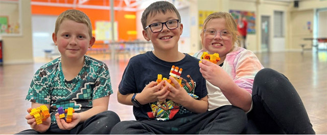 three children sat in school hall