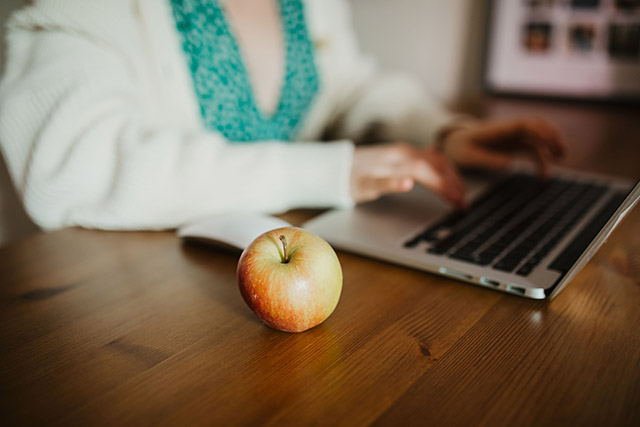 woman working at laptop with apple next to her