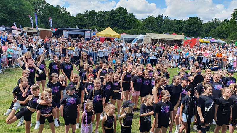 a large group of children in a dance group before a crowd of people